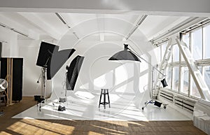 Professional lighting equipment, flashes, c-stands on a cyclorama in modern photo studio with a huge windows. Octabox