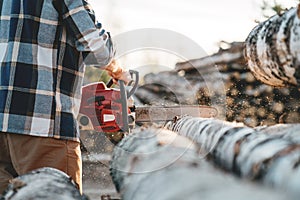 Professional lumberman worker using chainas on sawmill