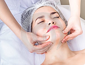 Professional lymphodrainage facial massage The cosmetologist is touching the client`s chin