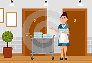 Professional maid standing at trolley with clean linen in hotel. Hotel room service worker in uniform, female