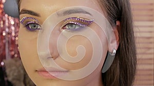 A professional make-up artist applies special rhinestones to the eyes and eyelids of a young beautiful girl model
