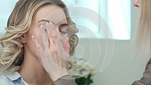 Professional make-up artist applying cream base eyeshadow primer to model eye