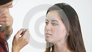 Professional make-up artist applying eyeshadow to model eye using special brush. Natural makeup in salon. Beauty, makeup