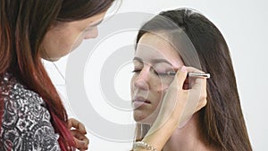 Professional make-up artist applying eyeshadow to model eye using special brush. Natural makeup in salon. Beauty, makeup