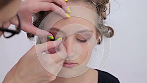 Professional make-up artist applying false eyelashes on model`s eyes