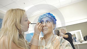 A professional make-up artist paints on the eyelids of the model. Preparation for an artistic photo shoot