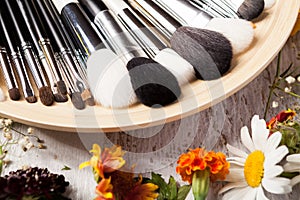 Professional Make up brushes on plate next to wild flowers