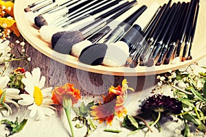 Professional Make up brushes on plate next to wild flowers