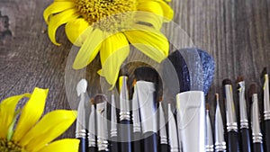 Professional make-up brushes on table next to sunflowers