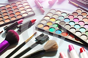 Professional make up set: eyeshadow palette, lipstick, make-up brushes and many cosmetics close up. Film and flare effect