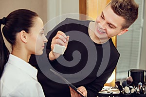 Professional makeup artist working with beautiful young woman