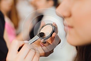 Professional makeup artist working with beautiful young woman.