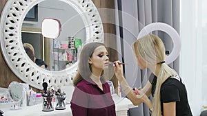 Professional makeup artist working on young girl creating natural look in beauty salon