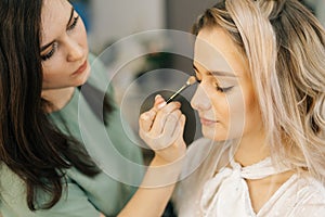 Professional makeup artistes working with beautiful young woman in dressing room photo