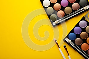 Professional makeup palette with brushes on yellow background