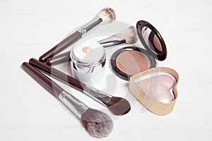 Professional makeup tools on white wooden background.