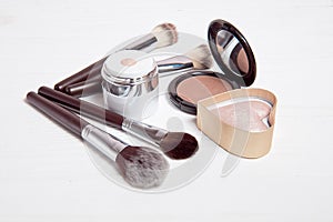 Professional makeup tools on white wooden background.