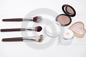 Professional makeup tools on white wooden background.