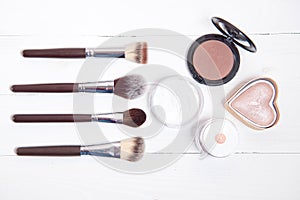 Professional makeup tools on white wooden background.