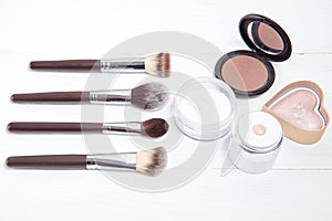 Professional makeup tools on white wooden background.