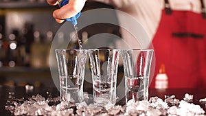 Professional male bartender pouring alcoholic drink in a shot glasses in a nightclub