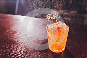 Professional male bartender spraying on the delicious transparent red cocktail in the glass on the bar counter in the