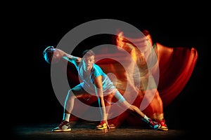Professional male basketball player in blue uniform playing basketball isolated over dark studio background in mixed