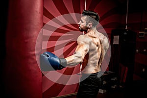 Professional male boxer fighting and training in gym. Strong, muscular man training and boxing