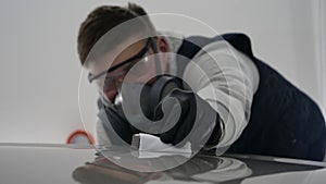 A professional male boy master of ceramics of a car puts ceramics on a car using a fiber sponge rag in a puller, safety goggle