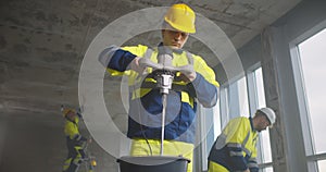 Professional male builder mixing plaster in bucket using electric mixer at new renovating apartment