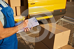 Professional male courier filling out delivery form on postal parcels