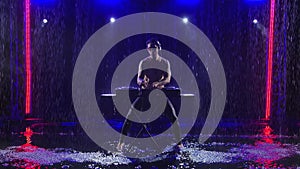 Professional male dj doing a live performance in dark studio under raindrops. Slow motion.