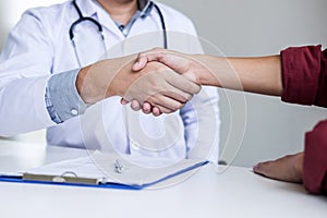 Professional Male doctor in white coat shaking hand with female