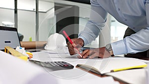 Professional male engineer doing a drawing for a project at his desk in his modern office. Construction manager working