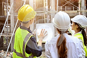 A professional male engineer explaining the building plan with a blueprint to a female architect