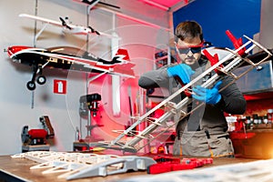 Professional male engineer or technician working on drone details in lab. Aircraft capable of GPS surveillance. Carbon.