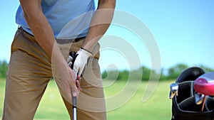 Professional male golf player holding iron club, standing in basic ball position