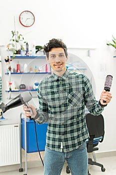 Professional male hairdresser with comb and hairdryer at hair salon.