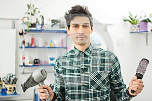 Professional male hairdresser with comb and hairdryer at hair salon.