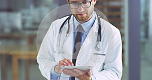 Professional male healthcare doctor on digital tablet smiling in a hospital. Portrait of happy and confident male