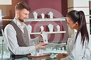 Professional male jeweler helping his female customer at the sto