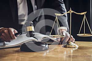 Professional Male lawyer or judge working with contract papers, documents and gavel and Scales of justice on table in courtroom,