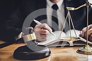 Professional Male lawyer or judge working with contract papers, documents and gavel and Scales of justice on table in courtroom,