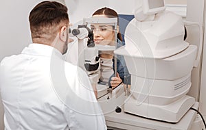 Professional male oculist sitting opposite his patient