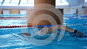 Professional male swimmer practising in swimming pool. Young sportsman swimming in pool. Slow motion