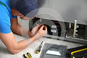 Professional male technician repairing broken refrigerator