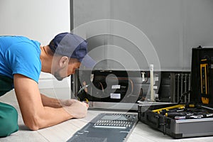 Professional male technician repairing broken refrigerator