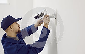 Professional male technician repairs or installing cctv camera system on wall inside house.