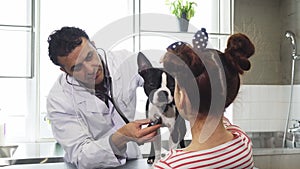 Professional male vet examining dog of a little girl at his office