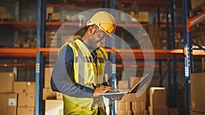 Professional Male Worker Wearing Hard Hat Holding Laptop Computer Checking Stock and Inventory in